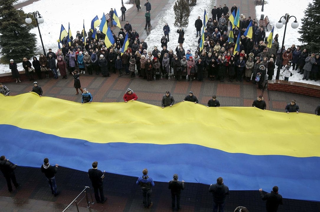 Varios ciudadanos sostienen una gran bandera ucraniana en foto de archivo de. /ROMAN PILIPEY. EFE