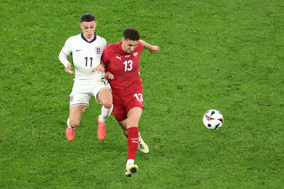 El jugador inglés Phil Foden (i) en acción contra el serbio Milos Veljkovic durante el partido del grupo C de la Eurocopa 2024 entre Serbia e Inglaterra en Gelsenkirchen, Alemania. EFE/EPA/GEORGI LICOVSKI