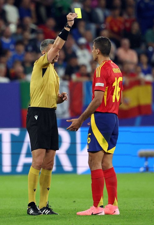 Referee Slavko Vincic (L) muestra amarlla a Rodrigo Hernández, centrocampista de la selección española en Gelsenkirchen. Alemania. EFE/EPA/CHRISTOPHER NEUNDORF