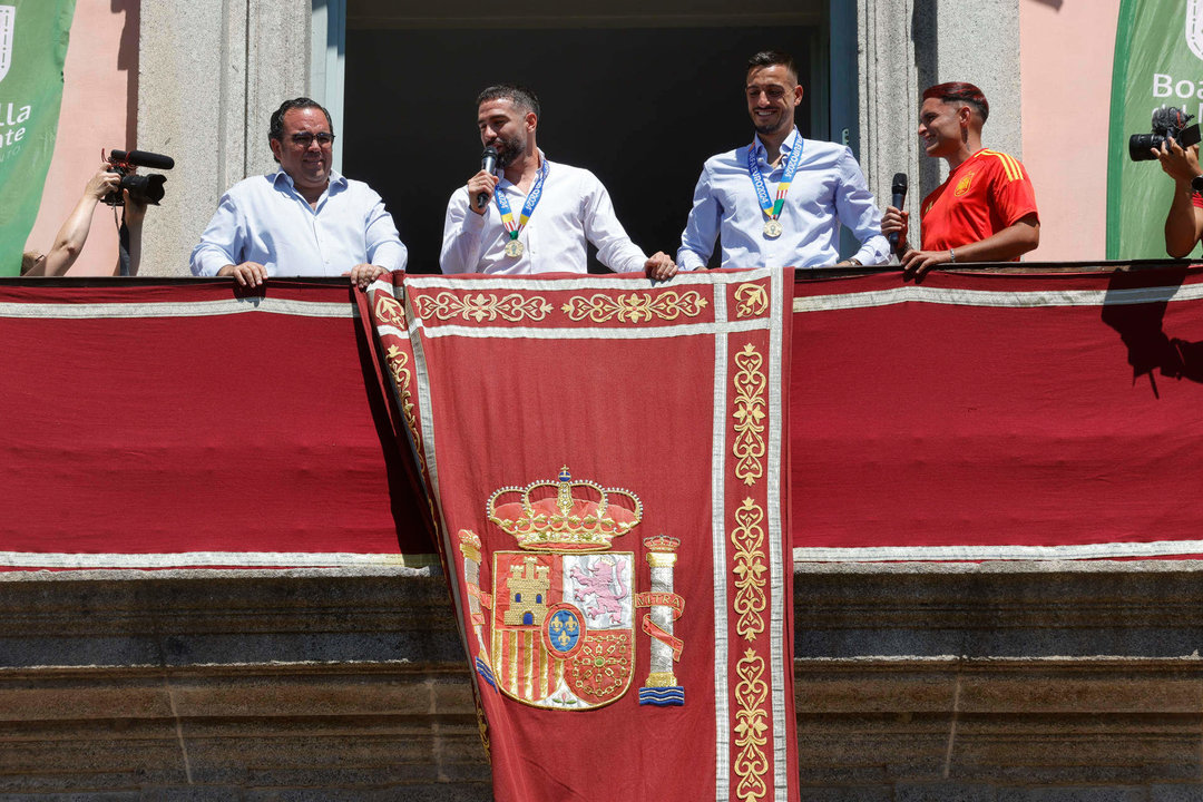 Los jugadores de la selección española de fútbol Dani Carvajal (c-i) y Joselu (c-d), vecinos de Boadilla del Monte, junto al alcalde de la localidad, Ignacio Vázquez Casavilla (i), mientras saludan a los aficionados desde el balcón del Ayuntamiento de Boadilla con motivo de su visita para celebrar la reciente victoria del equipo en la Eurocopa. EFE/ Zipi